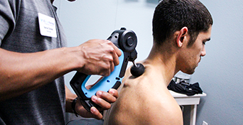 US Cryo technician applying theragun to lower neck of customer